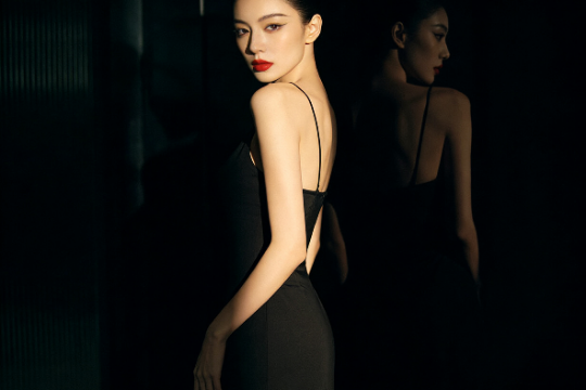 Elegant woman in black dress with red lipstick looking over shoulder.